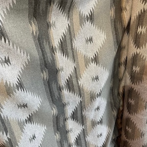 May include: Grey and beige fabric with a geometric pattern. The fabric has a woven texture and is folded in half.
