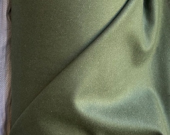 May include: A roll of olive green fabric with a soft, textured appearance. The fabric is draped, showing folds and shadows. The material appears to be a medium-weight textile, suitable for various sewing projects.