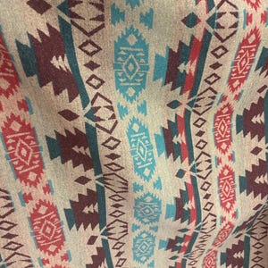 Peut inclure: Gros plan sur un tissu avec un motif géométrique répétitif. Le motif présente des rayures verticales avec des couleurs alternées de rouge, sarcelle et bordeaux sur un fond beige. Le motif comprend des losanges et des zigzags.