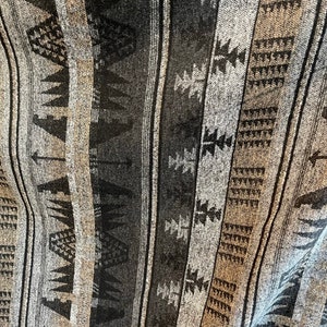 May include: A close-up of a woven fabric with a geometric pattern in shades of grey, black, and brown. The fabric has a textured surface and a slightly faded appearance.