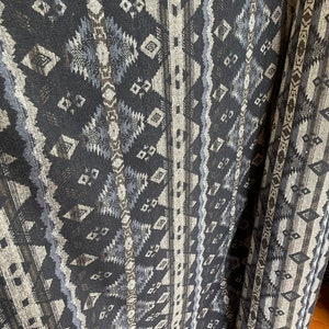 May include: Black fabric with a geometric pattern in shades of gray and brown. The fabric is folded and rolled up, showing the pattern from different angles.