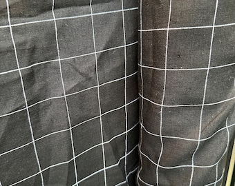 May include: Black fabric with a white grid pattern. The fabric is rolled up and the grid pattern is visible on both sides of the roll.