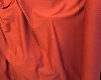 Peut inclure: Gros plan sur un tissu de couleur rouille, plié et roulé. Le tissu a une texture lisse et uniforme.