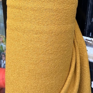 May include: A roll of mustard yellow fabric with a textured surface.
