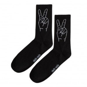 May include: Two black socks featuring a white hand gesture, the peace sign. The text "chelic socks" is printed in white on the side of each sock. The socks are presented against a white backdrop.