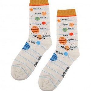 May include: Off-white socks with a solar system design. Each sock features planets like Mercury, Venus, Earth, Mars, Jupiter, and Saturn, with blue and orange accents. The socks have a mustard yellow cuff and the text "chetic socks".