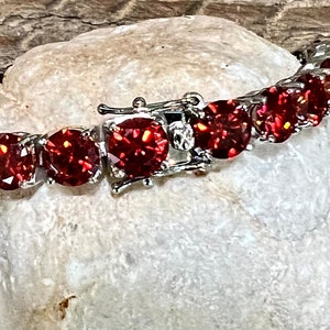 May include: A silver bracelet with a clasp and red round stones.