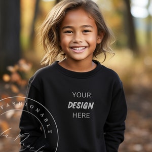 Puede incluir: Una persona joven lleva una sudadera negra con el texto "YOUR DESIGN HERE" impreso en la parte delantera. La sudadera es una maqueta para un diseño personalizado.