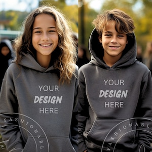 May include: Two gray hooded sweatshirts with the text "YOUR DESIGN HERE" printed on the front. The sweatshirts are shown on two people standing in front of a blurred background.