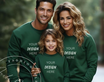 May include: A family of three wearing matching green crewneck sweatshirts with the text "Your Design Here" on each. The family is standing in a forest setting.