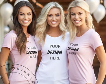 May include: Three women wearing t-shirts with the text "YOUR DESIGN HERE". Two women are wearing pink shirts, and one is wearing a white shirt. The shirts have a crew neck and short sleeves. The women are smiling.