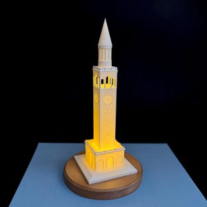 3D printed UNC Bell Tower LED light on wooden base, glowing warmly.