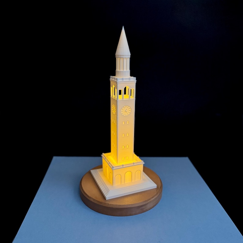 3D printed UNC Bell Tower LED light on wooden base, glowing warmly.