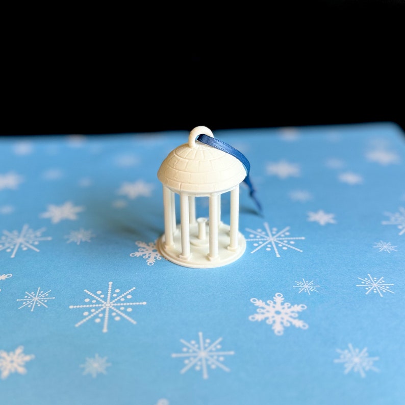 The smaller Old Well ornament, shown against a Carolina Blue background.