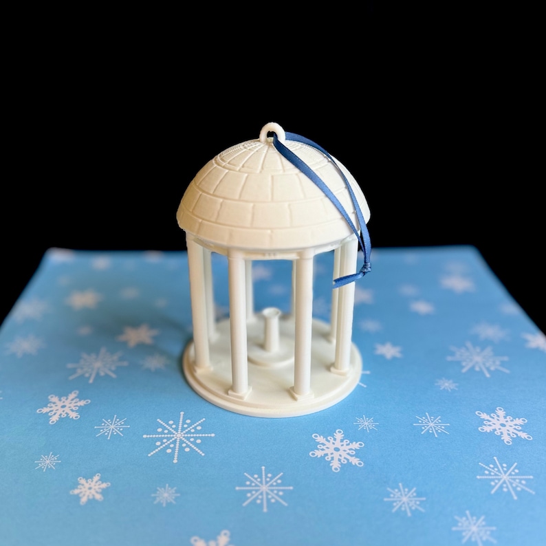The larger UNC Old Well ornament, shown in detail against a Carolina Blue background.