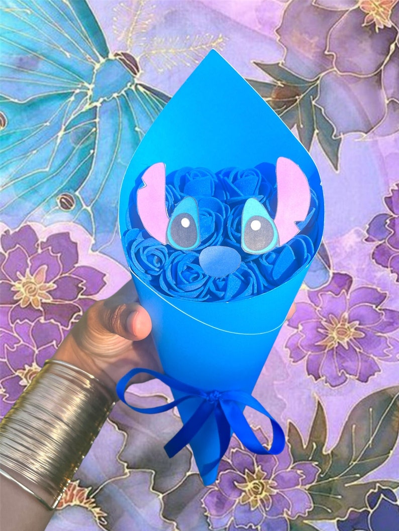 May include: A blue paper cone bouquet featuring blue roses and a Stitch character face. The bouquet is tied with a blue ribbon. The background has a floral and butterfly design in shades of purple, blue, and gold.