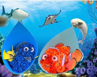 Könnte beinhalten: Ein blauer und orangefarbener Blumenstrauß mit den Figuren Dory und Nemo aus dem Film Findet Nemo. Die Blumen sind aus Stoff und in einer blauen und weißen Vase arrangiert.