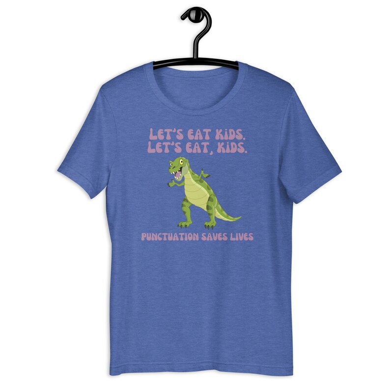 May include: A blue t-shirt featuring a green dinosaur graphic and the text "Let's eat kids. Let's eat, kids. Punctuation saves lives."