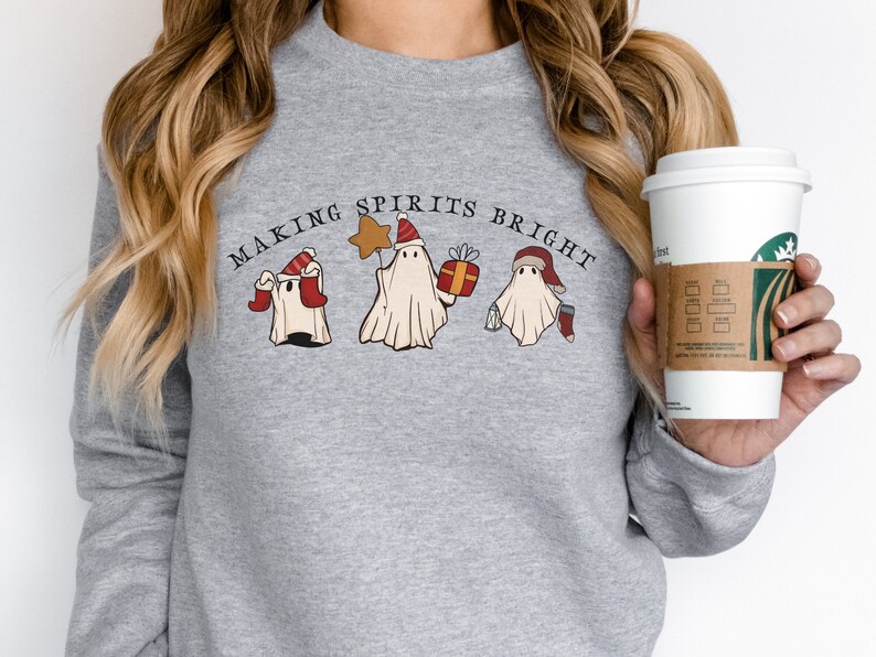 May include: Grey sweatshirt with the text "Making Spirits Bright" and a graphic of three ghosts wearing Santa hats. One ghost is holding a star, another is holding a gift, and the third is holding a cup of coffee.