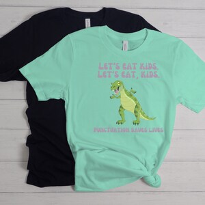 May include: A turquoise t-shirt with a green dinosaur graphic and the text "Let's eat kids. Let's eat, kids. Punctuation saves lives."