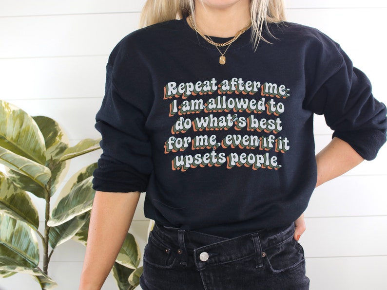May include: Black sweatshirt with a white graphic print that reads "Repeat after me: I am allowed to do what's best for me, even if it upsets people."