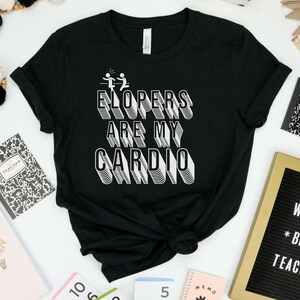 May include: Black t-shirt with white text that reads "ELOPERS ARE MY CARDIO" in a 3D style. The text is surrounded by two stick figures running.