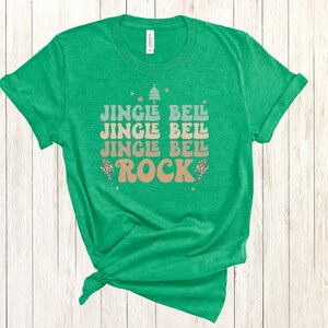 May include: Green t-shirt with a Christmas-themed graphic that says "Jingle Bell Jingle Bell Jingle Bell Rock" in a retro font.