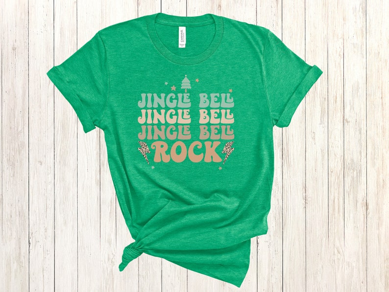 May include: Green t-shirt with a Christmas-themed graphic that says "Jingle Bell Jingle Bell Jingle Bell Rock" in a retro font.