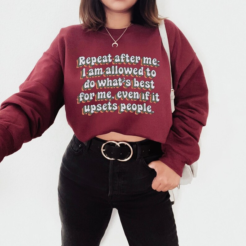 May include: A maroon cropped sweatshirt with the text "Repeat after me: I am allowed to do what's best for me, even if it upsets people." in a retro font.