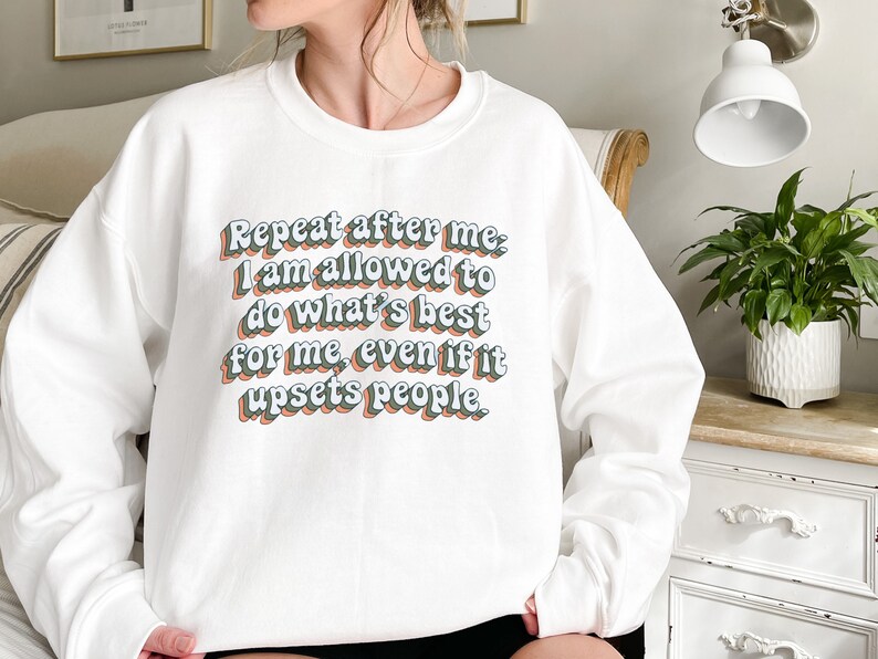 May include: White sweatshirt with the text "Repeat after me, I am allowed to do what's best for me, even if it upsets people." in a retro-style font.