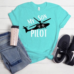 May include: A turquoise blue t-shirt with the text "My Son is a Pilot" and a silhouette of a helicopter.