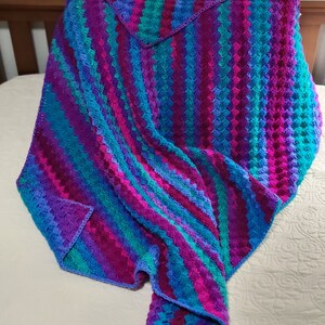 May include: A colorful crocheted blanket with stripes of purple, blue, and teal.