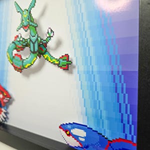 Puede incluir: Una pieza de arte de p&iacute;xeles enmarcada con tres personajes de Pok&eacute;mon: un Pok&eacute;mon de tipo agua verde y azul, un Pok&eacute;mon de tipo fuego rojo y negro y un Pok&eacute;mon de tipo agua azul y blanco. El fondo es un dise&ntilde;o pixelado azul y blanco.