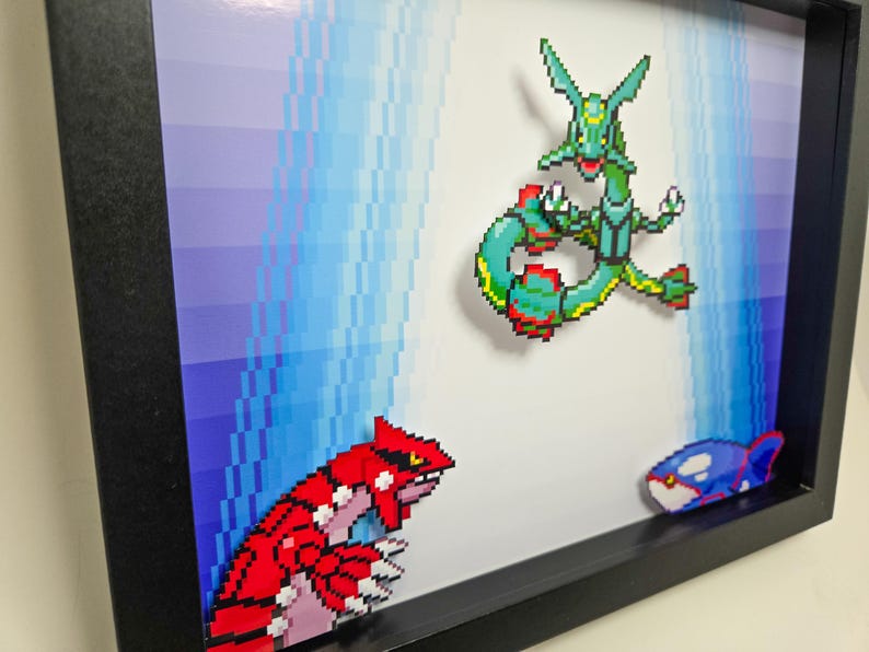 Puede incluir: Una impresi&oacute;n de arte de p&iacute;xeles enmarcada con tres personajes de Pok&eacute;mon: un Pok&eacute;mon de tipo agua verde y azul, un Pok&eacute;mon de tipo tierra rojo y rosa y un Pok&eacute;mon de tipo agua azul y negro.