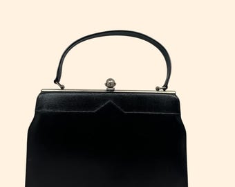 Bolsa vintage dos anos 1960 em couro sintético preto, com estrutura rígida e fecho de bola prateado.