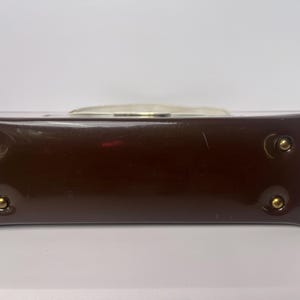 May include: A brown leather handbag with gold-toned hardware. The bag has a top handle and a flap closure.