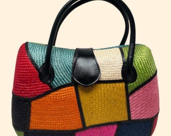 Puede incluir: Un bolso de mano de patchwork multicolor con asas y cierre de cuero negro. El bolso está hecho de material tejido y presenta una variedad de colores, incluyendo rojo, naranja, amarillo, verde, rosa y azul.