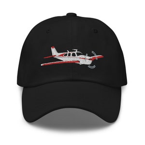 Könnte beinhalten: Schwarze Baseballkappe mit einem gestickten weißen und roten Flugzeug.