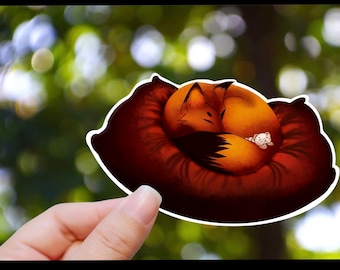 May include: A sticker featuring a cartoon fox curled up asleep on a red pillow. The fox is orange and brown with a white belly. A small white mouse is curled up asleep next to the fox.