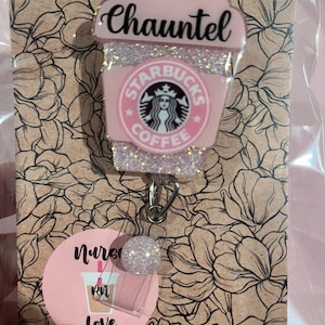 May include: Pink and white glitter Starbucks coffee cup with the name "Chauntel" on the top and a nurse badge holder with a pink and white glitter coffee cup with the text "Nurse Love" and a pink "RN" on it.