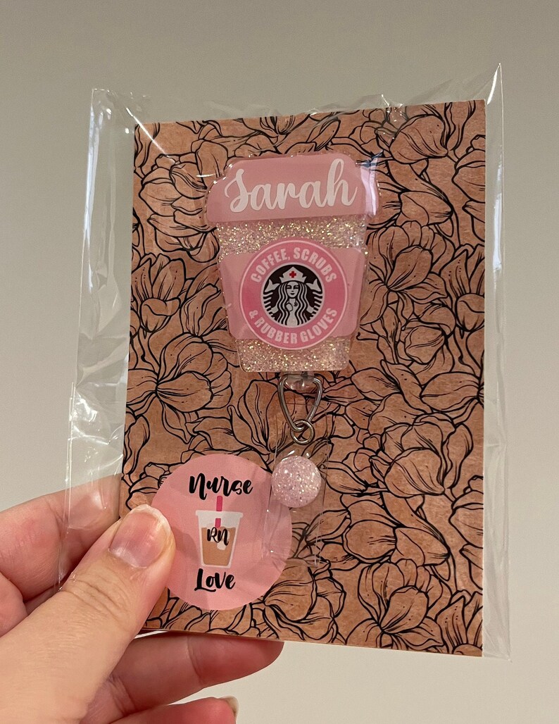 May include: Pink and white coffee cup charm with glitter and the text "Sarah, Coffee, Scrubs & Rubber Gloves". The charm is attached to a pink and white circle with the text "Nurse RN Love".