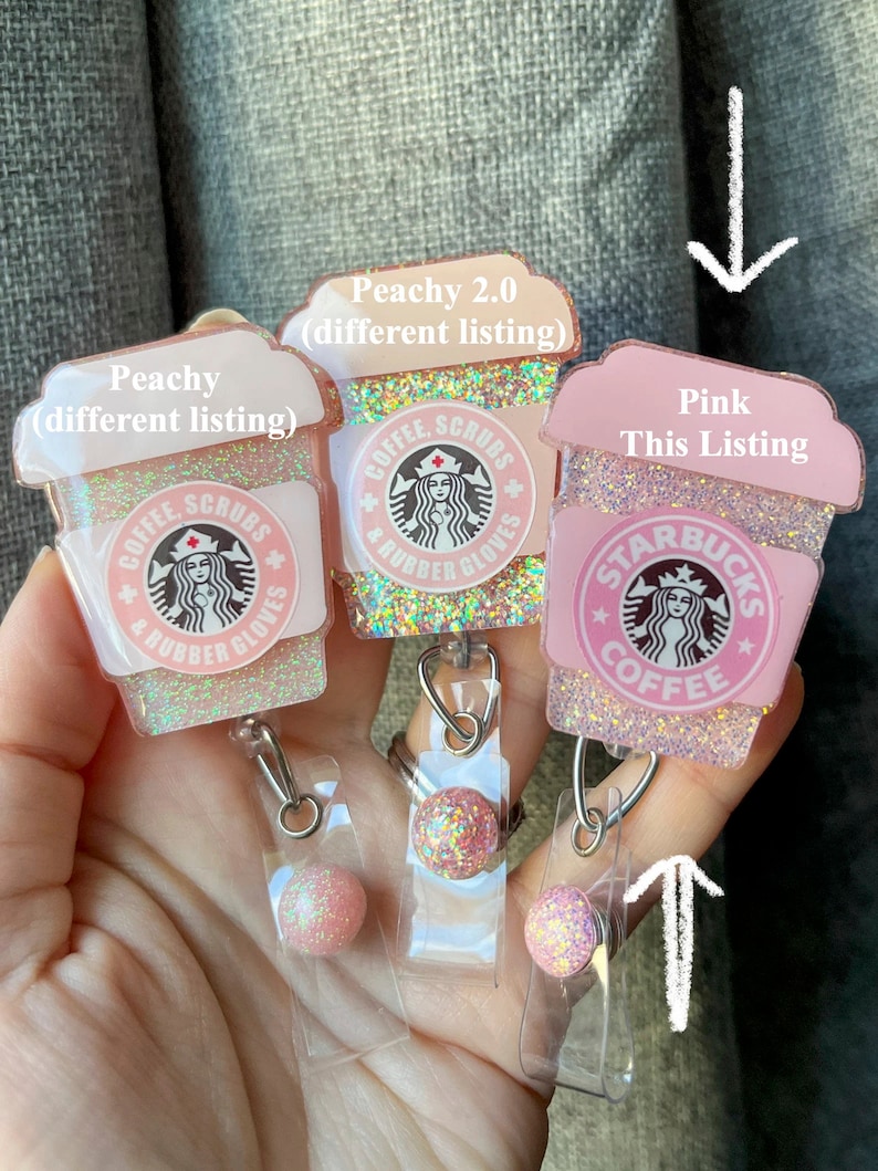 May include: Three pink and white glitter coffee cup themed retractable badge holders with a clear plastic badge holder and a pink glitter ball charm. The text on the cups reads "Coffee, Scrubs & Rubber Gloves" and "Starbucks Coffee".