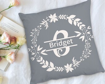 May include: Grey throw pillow with a white floral wreath design and the name "Bridget" in a white banner.