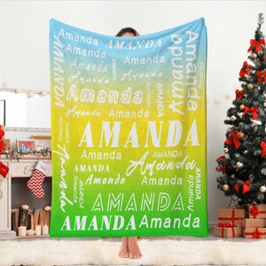 May include: A personalized blanket with the name "Amanda" in various fonts and sizes. The blanket features a gradient background of blue, yellow, and green. The word "Amanda" is repeated throughout the design, creating a custom and unique gift.