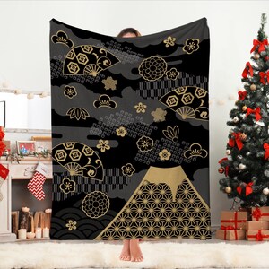 May include: Black and gold throw blanket with a Japanese-inspired design featuring a mountain, fans, flowers, and geometric patterns.