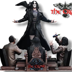 Può includere: Una figura in bianco e nero di The Crow dal film The Crow, in piedi su una base di legno con altre due figure. La figura di The Crow tiene un corvo nella mano sinistra e indossa una giacca di pelle nera e pantaloni. La base ha le parole "The Crow" scritte su di essa.