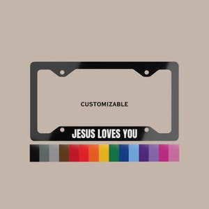 May include: Black license plate frame with the text "JESUS LOVES YOU" in white. The word "CUSTOMIZABLE" is above the opening. A color palette of options is shown below the frame.