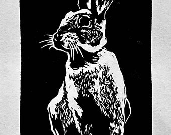 May include: Black and white linocut print of a rabbit sitting with its ears up. The print is titled "Bunny" and signed and dated "2023".