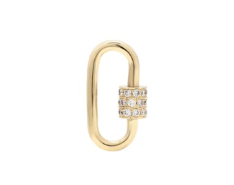 Puede incluir: Un cierre ovalado de color dorado con un charm cilíndrico incrustado con pequeños diamantes transparentes.
