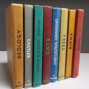 Könnte beinhalten: Eine Reihe von zehn bunten Hardcover-Büchern mit Titeln wie "Geologie", "Schlösser", "Gräser, Seggen & Binsen", "Katzen", "Unbemannte Raumfahrt", "Bäume", "Vögel" und "Fußball".